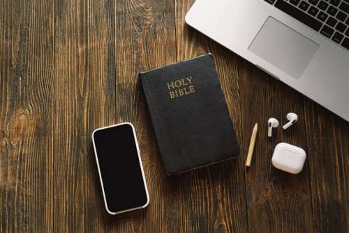 Study Bible worship online concept. Church online Sunday new normal concept. Bible, cell phone and earbuds on a wood background. Home church during quarantine coronavirus